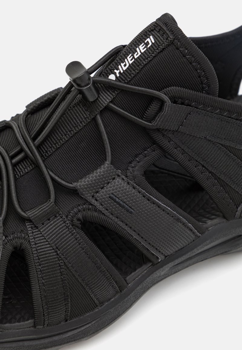 Zwarte sandaal met elastische banden en een gestructureerd oppervlak. Voorzien van een rubberen zool en een klittenbandsluiting voor een verstelbare pasvorm.