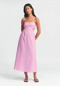 Vaaleanpunainen leikattu mekko neliömäisellä pääntiellä, ohuilla olkaimilla ja sivuleikkauksilla. Lattiatason muotoilu, jossa on sileä ja kevyt kangas.