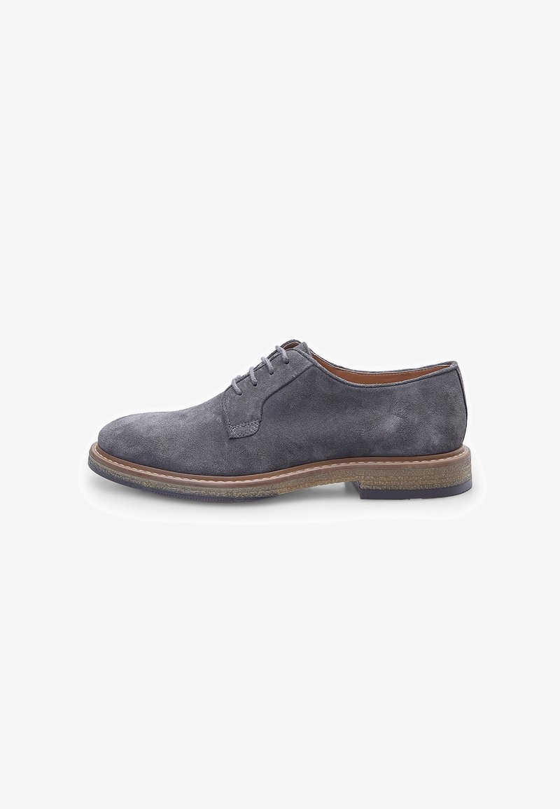 Scarpe derby in suede grigio con punta tondeggiante, sei occhielli per i lacci e suola in contrasto marrone. Texture liscia e dettagli di design minimalisti.