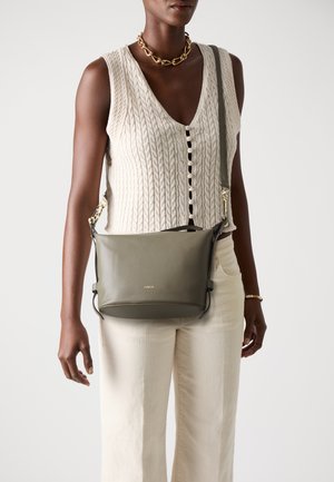 Maslinasto zeleni kožni crossbody bag s glatkom teksturom, podesivim remenom i zlatnim detaljima. Na prednjoj strani se nalazi logotip brenda.
