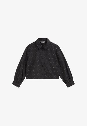 Chemise courte noire à manches longues avec petits pois blancs, boutons sur le devant et col.