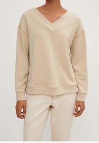 Sudadera beige de manga larga con un escote en V ancho, puños y dobladillo acanalados; hecha de un material suave y liso con un ajuste relajado.