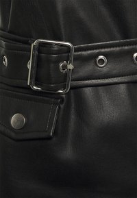 Czarny skórzany pasek z prostokątną srebrną klamrą, z licznymi metalowymi oczkami i przeszyciem na pasku.