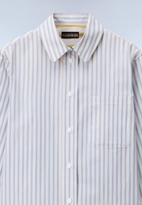 Light blue and white striped button-up shirt with a collar, single chest pocket, and white buttons. Made from smooth fabric with a relaxed fit.
