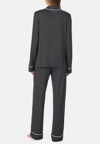 Set di pigiama grigio con maniche lunghe e pantaloni, con piping bianco lungo il colletto e i polsini. Realizzato in tessuto morbido e liscio.