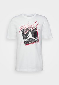 Camiseta blanca de manga corta con un gráfico rojo y negro de Air Jordan y la palabra "Flight" en rojo en un estilo cursiva cruzando el pecho.