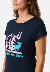 T-paita lyhythihainen tummansininen, jossa on graafinen kuva hirvestä puiden ja vuorten keskellä vaaleanpunaisena ja vaaleansinisenä. Teksti lukee "Ulkoiluseikkailu".