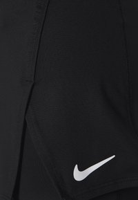 Pantalones cortos deportivos negros de tela elástica con una abertura lateral, detalles de costura y un logo de Nike blanco en la parte inferior izquierda.