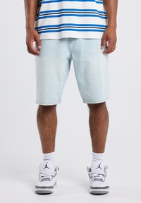 Light blue denim shorts with a relaxed fit and cuffed hems, paired with white socks and gray-and-white athletic sneakers.