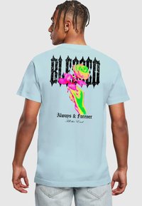 Himmelblaues Baumwoll-T-Shirt mit einem grafischen Design aus bunten Rosen und einer Hand, mit dem Text "BLESSED" und "Always & Forever" in fetter schwarzer Schrift.