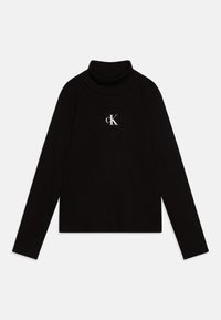 Črni rebrasti pulover s kolebnico in dolgimi rokavi. Ima bel logotip "cK" v središču prsnega dela. Gladka tekstura, oprijet kroj.