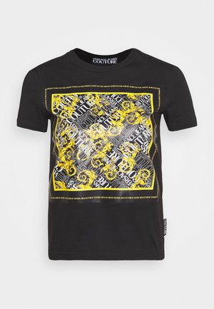 T-shirt noir à manches courtes avec un grand motif carré présentant des volutes baroques jaunes et des motifs de texte blancs "Versace Jeans Couture".