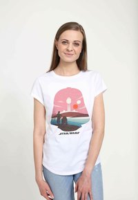 Bílý tričko s krátkým rukávem s grafickým potiskem růžové krajiny se dvěma postavami a siluetou vesmírné lodi, označený "STAR WARS."
