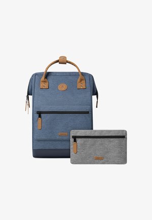 Blue fabric backpack features brown leather accents, a top handle, and front zip pockets. Includes a small gray zip pouch with similar texture.