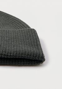 Grijze gebreide muts met een brede geribbelde boord. Gemaakt van zacht materiaal met een textuur die licht pluizig aanvoelt.