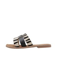 Chanclas con un diseño a rayas en blanco y negro con textura de pelo, complementadas por una correa negra lisa y una suela plana marrón.