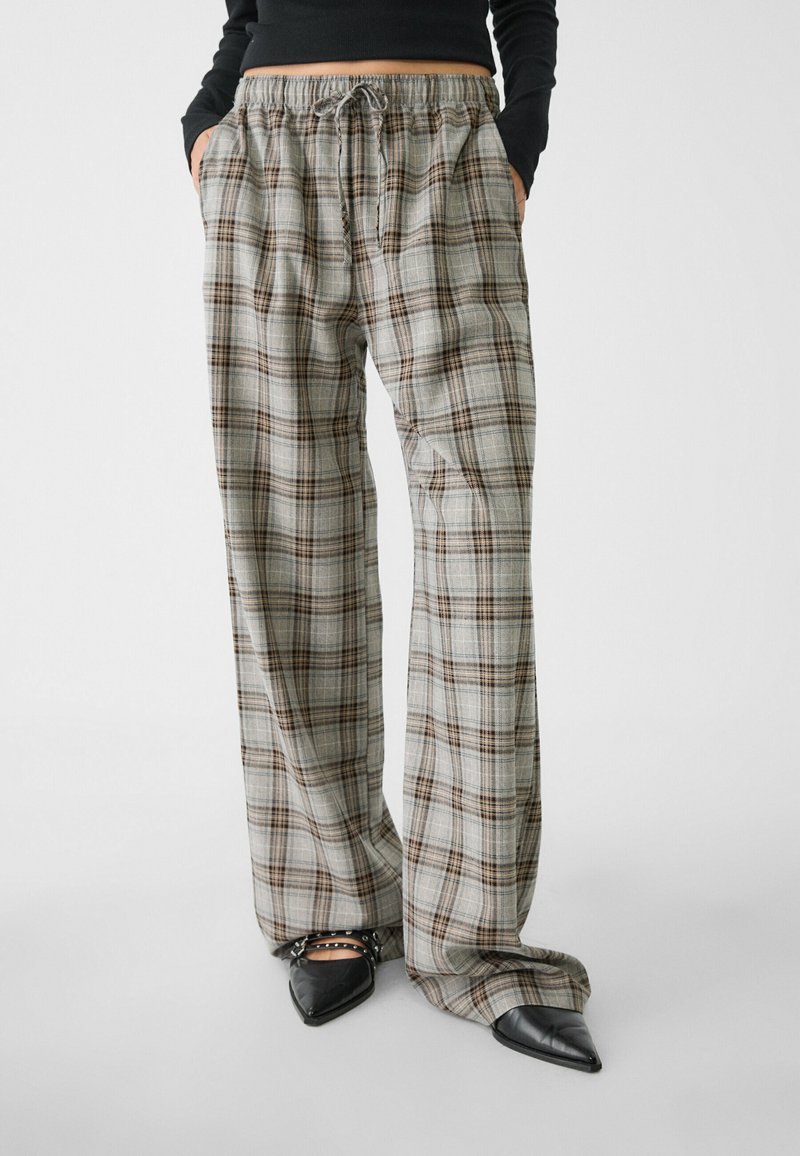 Weite Hose aus leichtem Material mit einem beige-braunen Karomuster, elastischem Bund und seitlichen Taschen.