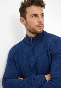 Maglione blu lavorato a maglia con collo alto e chiusura a zip, polsini a coste e finitura testurizzata.