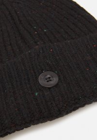 Gorro de punto negro con textura acanalada, motas de color y un detalle de dos botones en negro. El material parece suave y cálido.