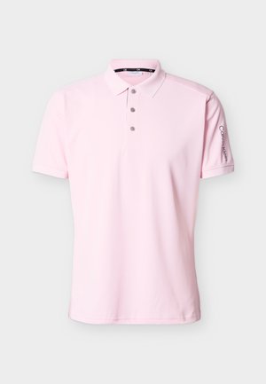 Svetloružové krátke polo tričko s tromi gombíkmi a logom Calvin Klein vertikálne potlačeným na ľavom rukáve.