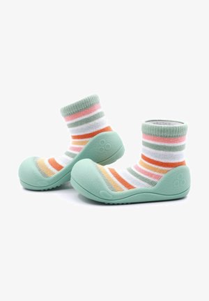 Zapatillas de goma verdes con un acabado texturizado y un calcetín de algodón a rayas multicolor adjunto, que presenta colores pastel en rosa, naranja y blanco.