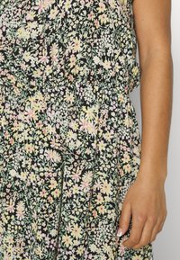 Vestido floral com uma base preta adornada com flores em tons pastéis de amarelo e rosa, cintura elástica e uma tela macia e texturizada.