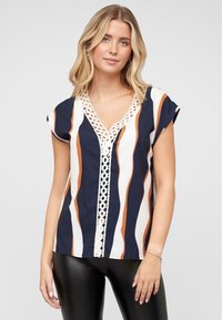 Blouse rayée bleu marine et blanche avec des accents oranges, dotée d'un col en V et de dentelle sur le devant. Manches courtes et coupe décontractée.