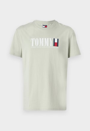 Svijetlozelena pamučna majica s okruglim izrezom. Ima bijeli tiskani natpis "TOMMY" i naglaske logotipa u plavoj i crvenoj boji. Kratak rukav.