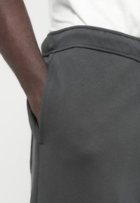 Γκρι φόρμα με απαλυ υφή, διαθέτει φαρδιά μέση και τσέπες. Το ύφασμα φαίνεται λείο και ελαστικό, κατάλληλο για καθημερινή χρήση.