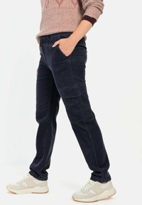 Marine cargo broek met een zachte textuur, voorzien van meerdere zakken. Gecombineerd met lichtgekleurde sneakers, gestyled met een roze gebreide trui.