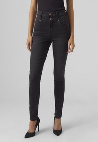 Černé skinny džíny s vysokým pasem vyrobené z denimu, s dvěma předními kapsami, kovovými knoflíkovými detaily a hladkou texturou.