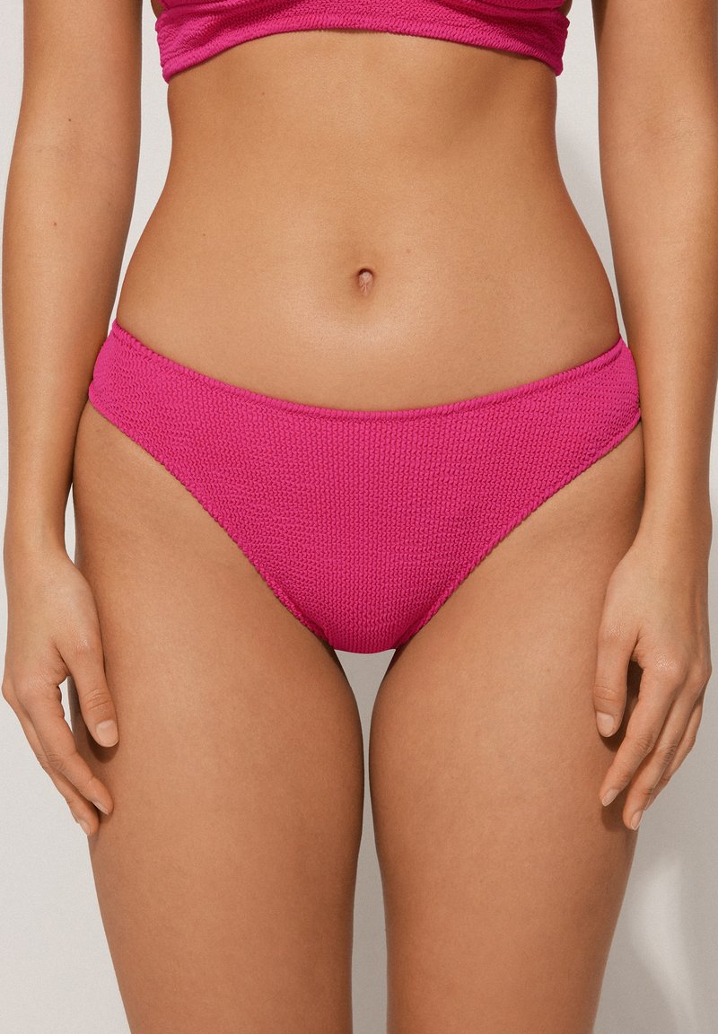 Bas de bikini rose texturé avec un design taille basse. Le tissu présente un motif tissé et des bords lisses pour un ajustement confortable.