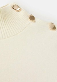 Bluză crem cu decolteu cu dungi, având trei accente neregulate de nuanță aurie lângă guler. Material cu textură netedă.