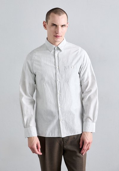 Chemise boutonnée rayée gris clair en coton, avec une poche poitrine unique et un col classique, assortie à un pantalon marron.