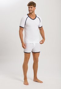 Bílý bavlněný top s krátkým rukávem ve tvaru V a odpovídající boxerkové šortky, s námořnickým modrým lemováním, lehkým materiálem a volným střihem.