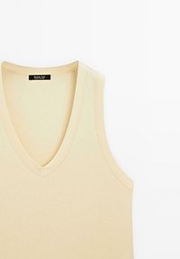 Beige gerippter Tank-Top mit V-Ausschnitt und breiten Trägern. Verfügt über eine subtile Textur und gestickte Details entlang der Kanten.