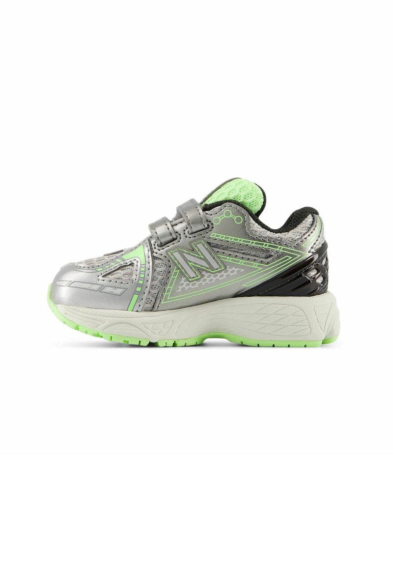 Silver athletic shoe with green accents, mesh upper, padded collar, double hook-and-loop straps, and textured sole for grip.