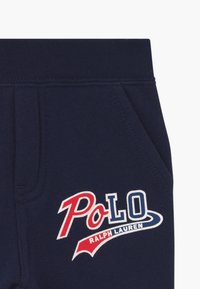 Joggers de algodón azul marino con el logo rojo y blanco de "Polo Ralph Lauren", con bolsillos laterales y cinturilla acanalada.