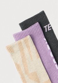 Kolm paari soonikkoes sokke: beežid mustriga, helelillad ja tumehallid valge tekstiga. Tekstuuriga kudumismaterjal kogu sokki ulatuses.