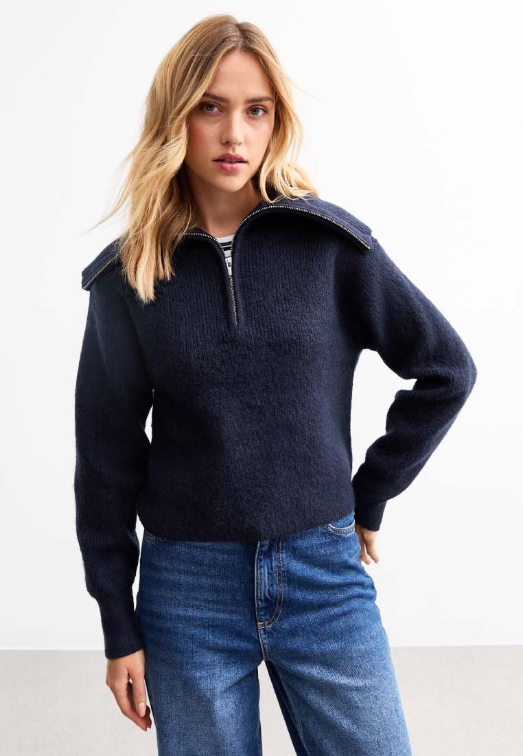 Marinblå julgross med en texturerad yta, bred krage och halvdragkedja fram. Matchas med blå denimjeans. Designad med långa ärmar.