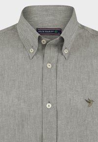 Camisa de lino gris claro con cuello abotonado, botones en color crema y un pequeño pájaro verde bordado en el lado izquierdo del pecho.