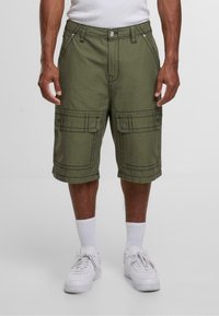 Olíva zöld, pamutkeverék cargo rövidnadrág, dupla elülső zsebekkel, varrott részletekkel és laza szabással. Fehér sportcipővel párosítva.