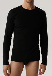 Czarna, długosleeve koszulka wykonana z gładkiego materiału. Posiada klasyczny okrągły dekolt oraz dopasowany krój. Minimalistyczny design bez wzorów.