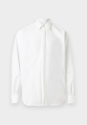 Λευκό πουκάμισο με μακριά μανίκια, κουμπωτό με κρυφά κουμπιά και κλασικό γιακά, παρουσιάζεται πάνω σε απλό φόντο.