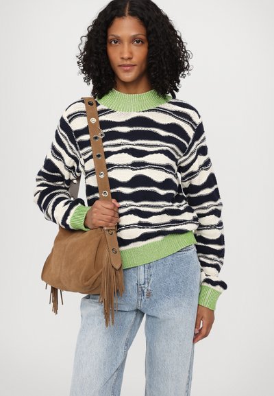 Maglione a righe blu navy e bianche lavorato a maglia, con colletto verde, abbinato a una borsa in suede marrone con frange e dettagli in bottone. Jeans azzurri.