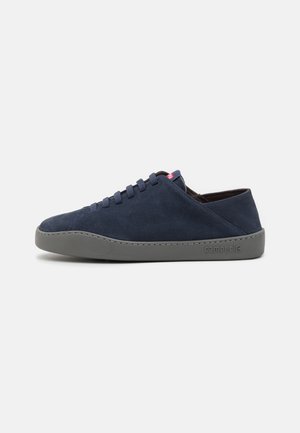 Navyblauwe suède sneakers met een ronde neus, grijze rubberen zool en bijpassende veters. Bevat een klein rood logo op de tong en een minimalistisch ontwerp.