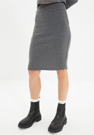 Woman wearing a grey ribbed knit pencil skirt, white socks, and black chunky ankle boots, standing against a plain white background.