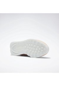 Semelle de chaussure avec une semelle extérieure en caoutchouc blanc texturé présentant des motifs de bande de roulement circulaires et rainurés pour l'adhérence et la durabilité.