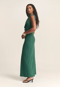 Maxikleid aus einfarbigem dunkelgrünem Stoff mit gerafftem Ausschnitt und taillierter Taille. Verfügt über ein ärmelloses Design und eine bodenlange Silhouette.