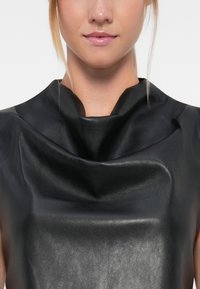 Top in pelle nera con design drappeggiato, texture liscia e scollatura rotonda, che crea un aspetto morbido ed elegante.